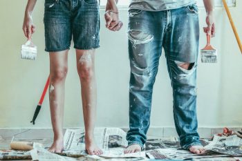 A man and woman covered in paint and holding paint brushes.